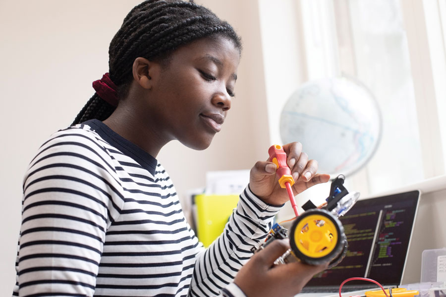 Photo of a student tinkering on a hand made RC vehicle